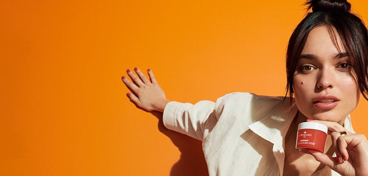 orange background with model holding new Ginzing Gel Moisturizer